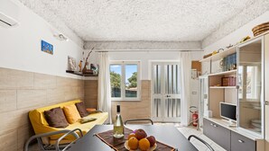 Una cocina moderna con una mesa de comedor, un sofá y vistas a través de puertas de vidrio.