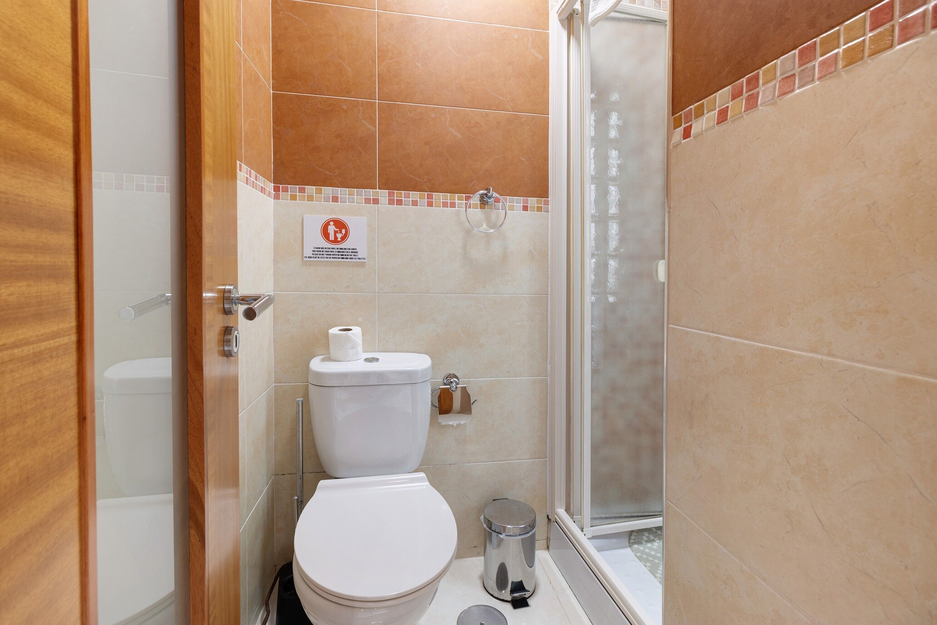 Un baño con inodoro, ducha y cubo de basura.