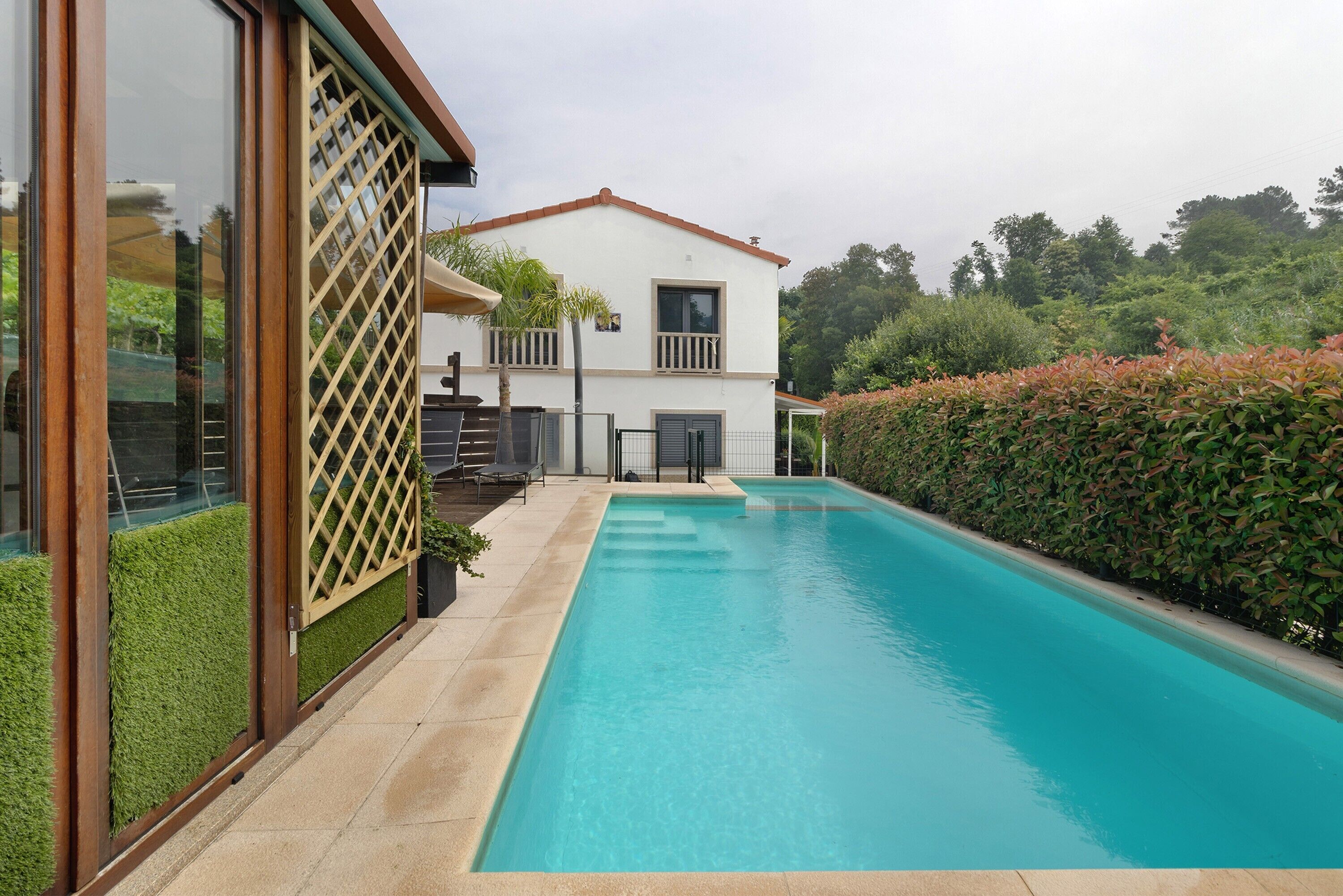A modern house with a swimming pool, a balcony, and a well-maintained garden.