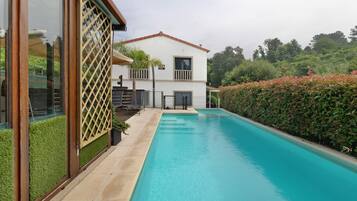 A modern house with a swimming pool, a balcony, and a well-maintained garden.