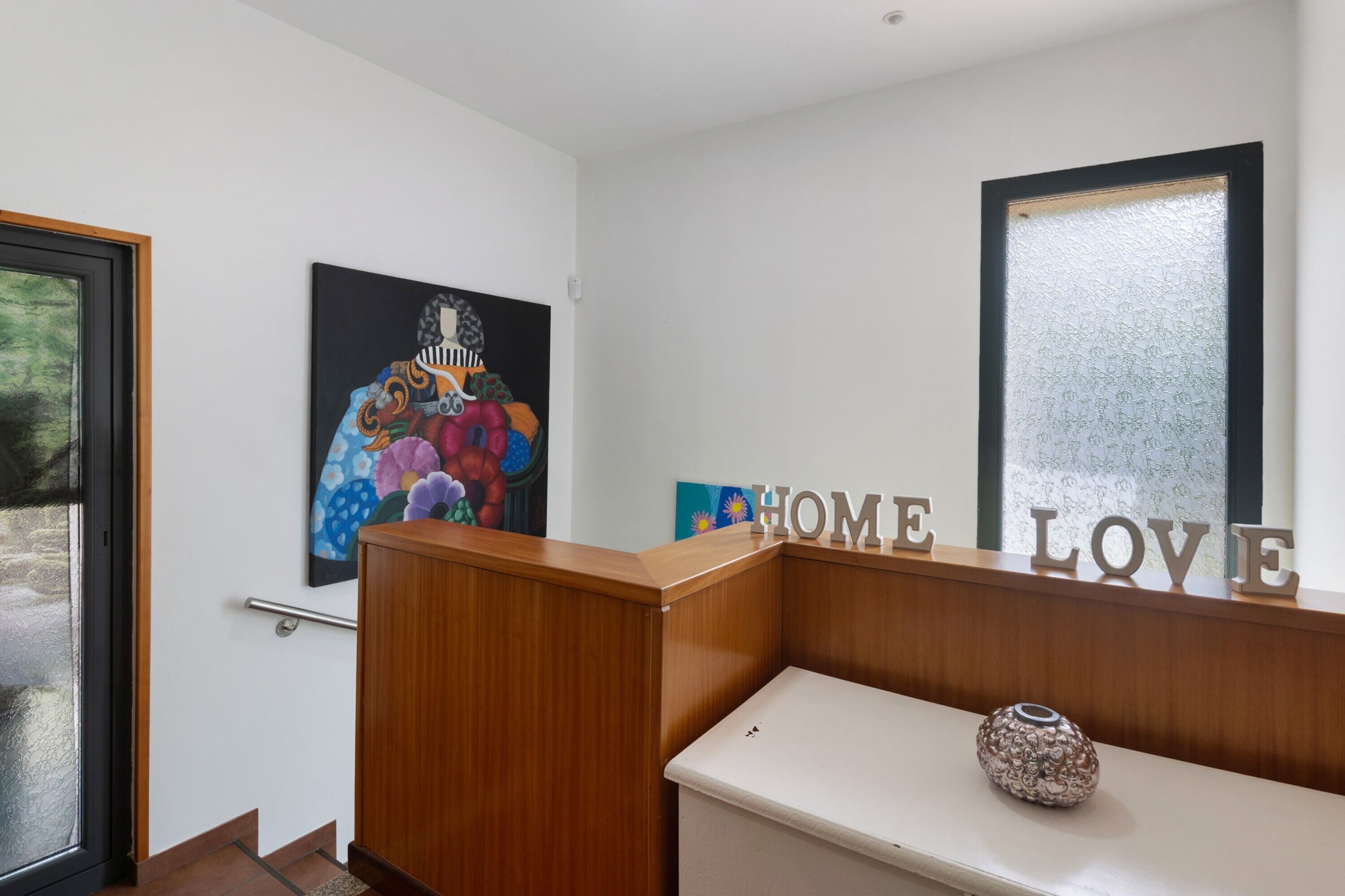 Ein Empfangstresen mit Holzoptik, einer Glastür und einer Wand mit der Aufschrift 'HOME LOVE'.