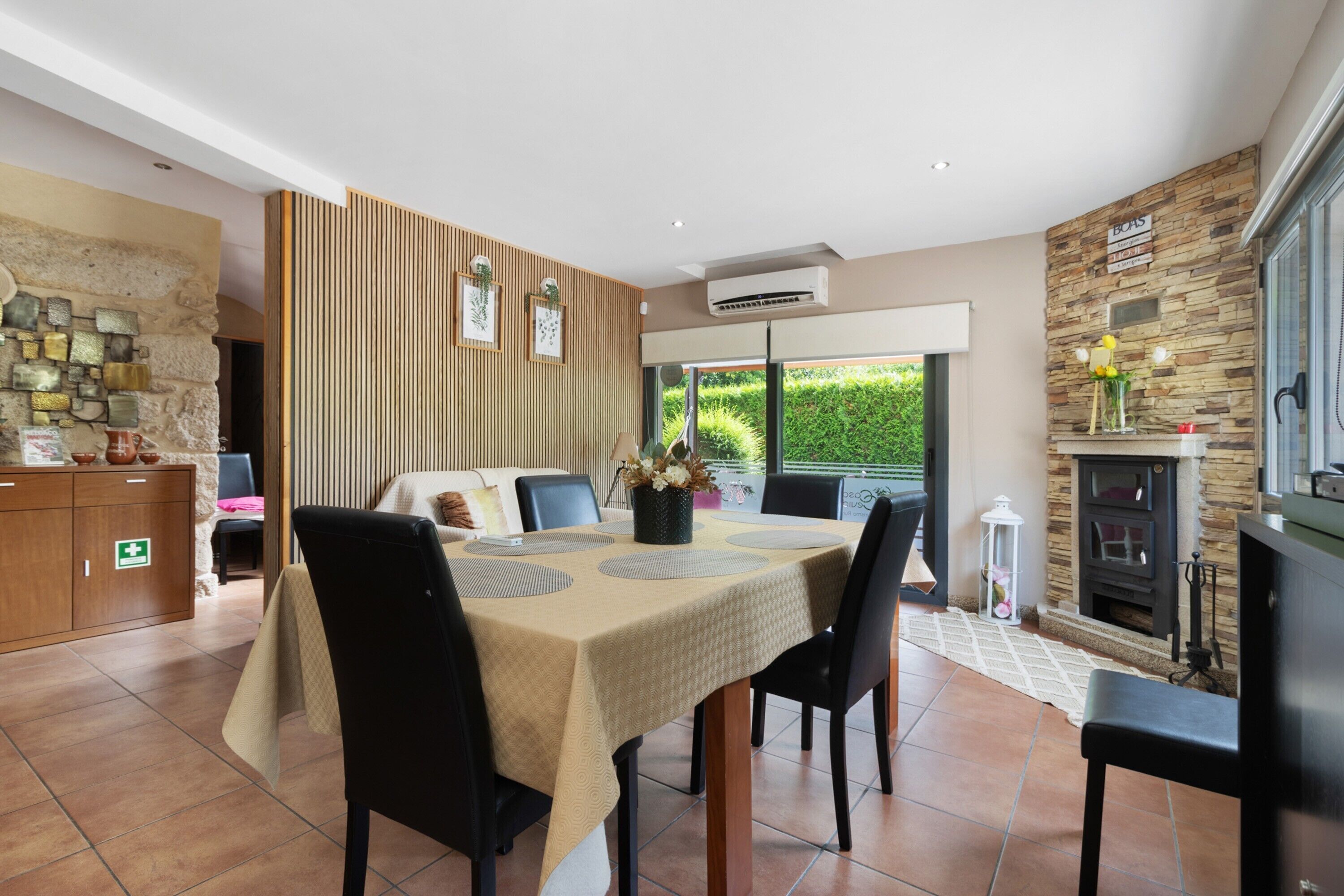 Un comedor con una mesa para cuatro, un sofá, una chimenea y una pared de piedra con un letrero.