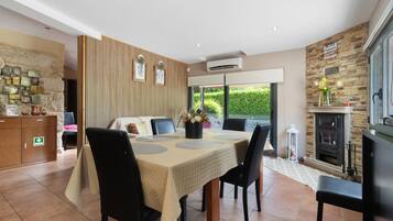 Un comedor con una mesa para cuatro, un sofá, una chimenea y una pared de piedra con un letrero.