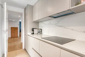 A modern kitchen with white cabinets, a marble backsplash, and a stainless steel countertop.