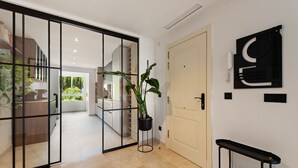 A modern interior with a sliding glass door leading to a kitchen, a potted plant, a wall-mounted phone, and a console table. - Apartment 'La Quinta Golf' with Sea View, Wi-Fi and Air Conditioning (Unknown)