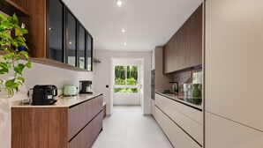 A modern kitchen with wooden cabinets, a coffee maker, and a view to the outdoors. - Apartment 'La Quinta Golf' with Sea View, Wi-Fi and Air Conditioning (Unknown)