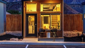 Un edificio moderno de dos pisos con cocina, comedor y una pequeña zona de estar al aire libre.