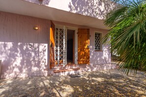 A house with a pink exterior, wooden doors, and a small porch.