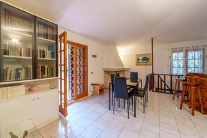 A dining area with a table and chairs, a bookshelf, and a fireplace.