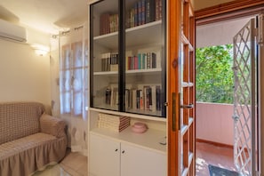 A room with a sofa, a bookshelf, a cabinet, and a door leading outside.