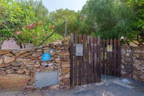A stone wall with a wooden gate, a sign indicating a holiday location, and a metal mailbox.