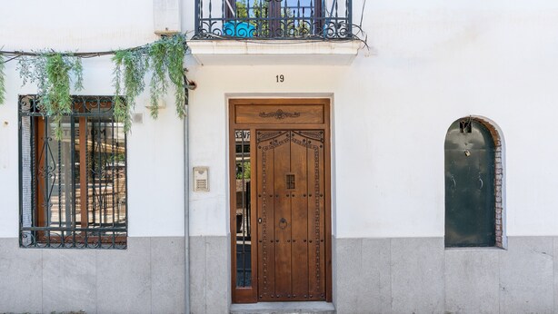 A building with a wooden door, a balcony with metal railings, and a small window.