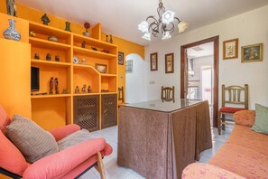 Una sala de estar con un sofá, una mesa de comedor y estantes con objetos decorativos.