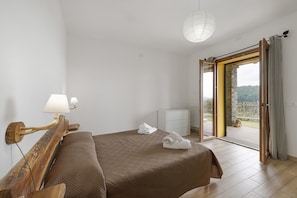A bedroom with a bed, a nightstand, a lamp, a radiator, and a view of the outdoors.