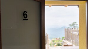 Habitación con el número 6 en la pared, una puerta de madera y vista a un patio exterior con mesa y sillas.