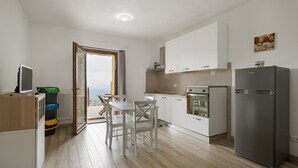 Una cocina moderna con armarios blancos, un refrigerador de acero inoxidable y una zona de comedor con sillas blancas.