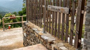 Una cerca de madera con un cartel, un muro de piedra y vistas a montañas.