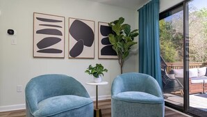 A modern living room with two blue armchairs, a small white table with a plant, and abstract art on the wall. - Neon Dream Lodge! Pickleball, Hot Tub, Theater (McGaheysville)