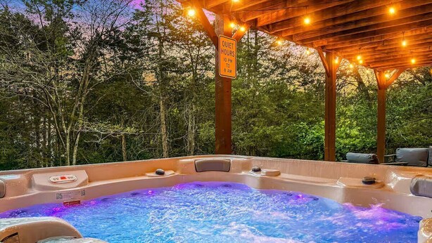 A hot tub with a sign indicating quiet hours from 10 PM to 8 AM. - Neon Dream Lodge! Pickleball, Hot Tub, Theater (McGaheysville)