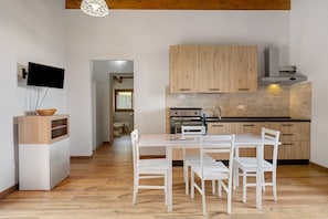 A modern kitchen with wooden cabinets, a built-in oven, and a dining area with white chairs. - Apartment 'Camera 1' with Mountain View, Private Terrace and Wi-Fi (Sasseta)