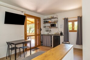 A compact kitchen with a dining area, a flat-screen TV, and a small refrigerator. - Studio 'Oltremare - Casa Fornelli' with Shared Pool, Wi-Fi and Air Conditioning (Riparbella)