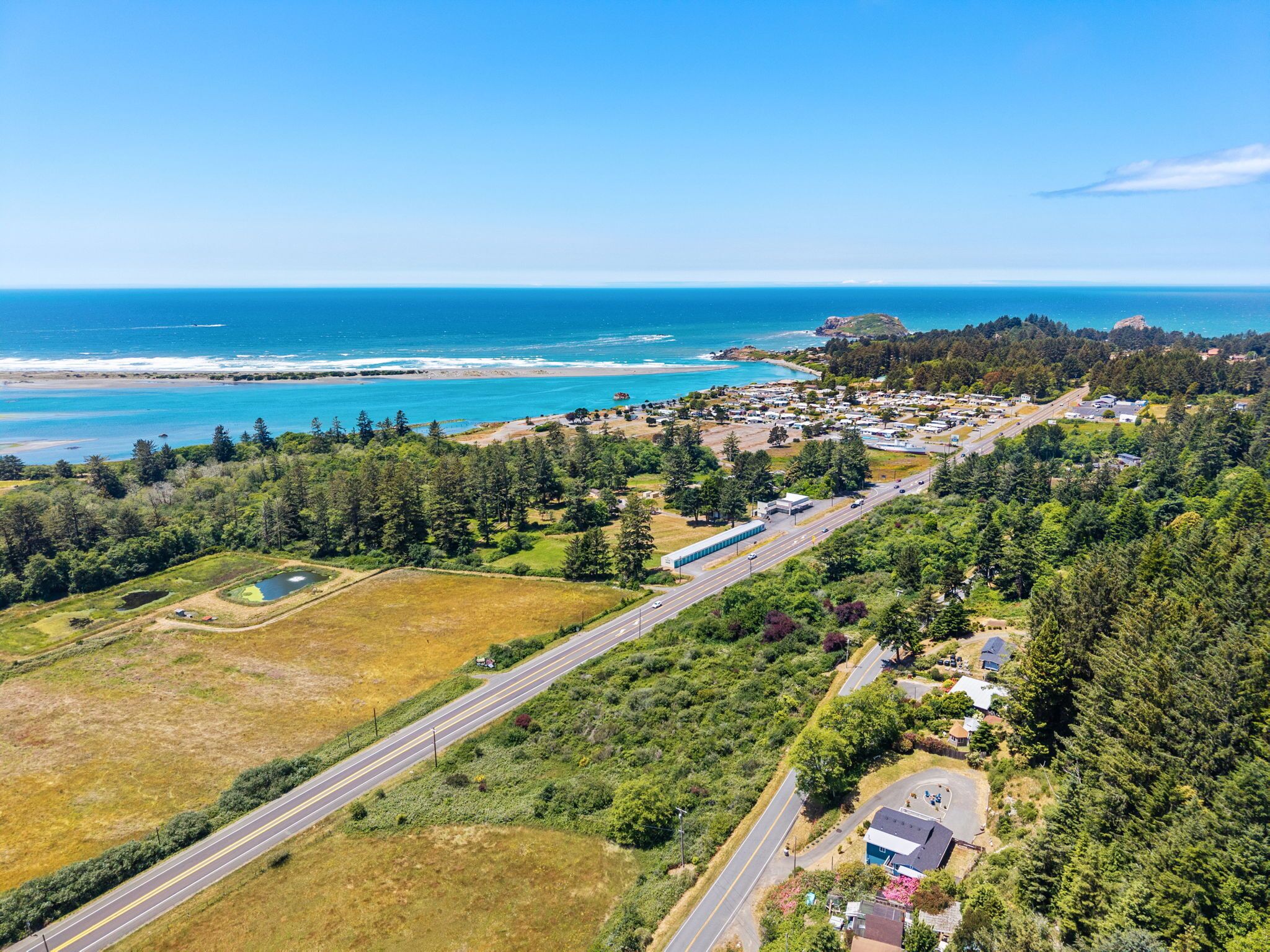 Vista aérea de un pueblo costero con una carretera principal, zonas residenciales y una playa.