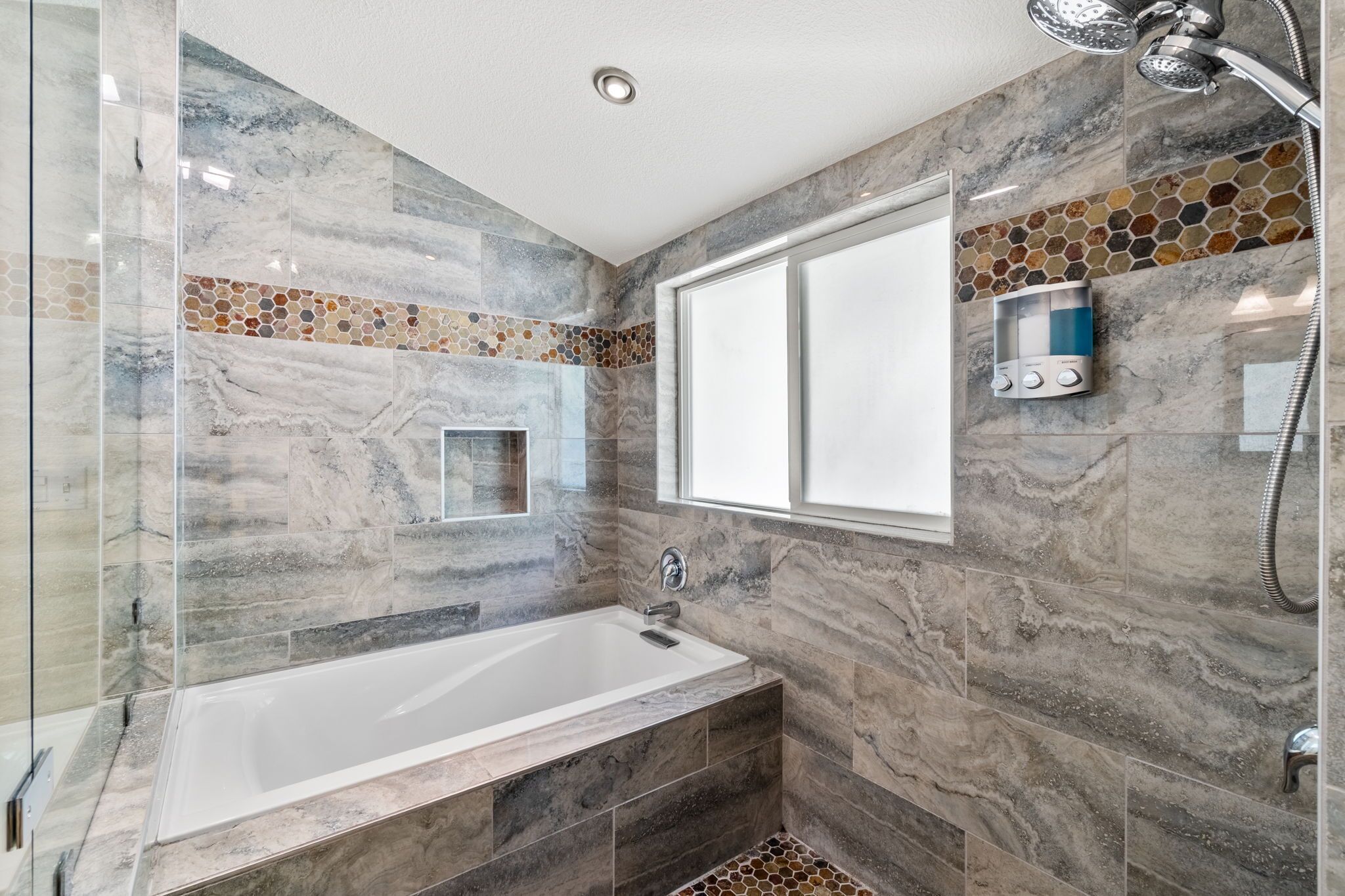 Un baño moderno con ducha envuelta en vidrio, una bañera independiente y un salpicadero de mosaicos.