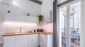 Una cocina moderna con armarios blancos, encimera de madera, microondas y una planta colgante.