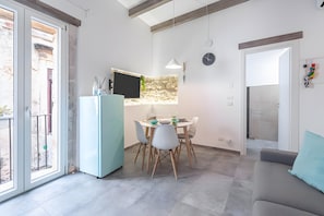 A modern kitchen with a dining area, a refrigerator, and a clock on the wall.