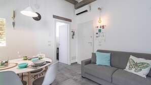 Una sala de estar moderna con un sofá gris, una mesa de comedor con sillas y una zona de cocina.