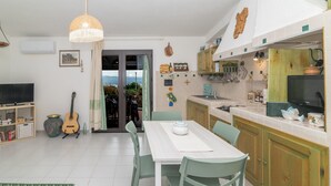 Un amplio salón con mesa de comedor, sillas, televisor y una guitarra.