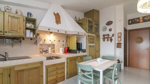 Una cocina con armarios de madera, una encimera blanca, una estufa y un comedor con mesa y sillas.