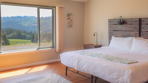 Un dormitorio con un ventanal grande, un cabecero de madera y una mesita de noche con lámpara.