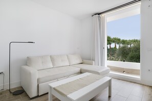 A modern living room with a white sofa, a small white table, and a floor lamp.