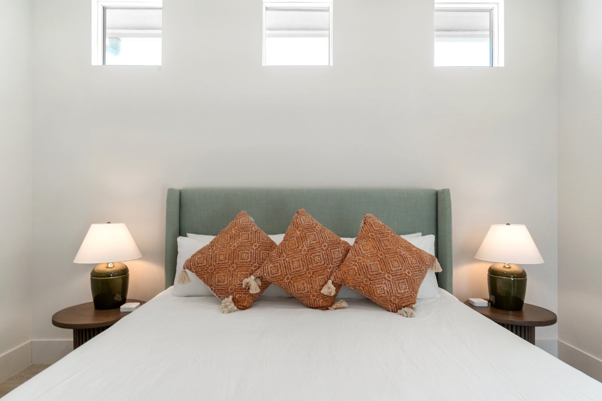 A hotel room with a bed, two nightstands, three patterned pillows, and two lamps.