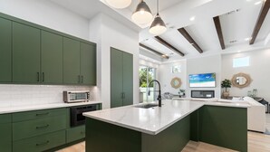 A modern kitchen with green cabinets, a large island, and a built-in oven. - NEW! Luxe Escape w/ Pool & Spa - Close to Beach (Naples)