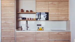 A modern kitchen with wooden cabinetry, a stainless steel microwave, and a white countertop.