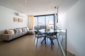 A modern living room with a glass dining table, a sofa, and a balcony with a view. - Vacation 'Kay Lava' with Mountain View, Wi-Fi and Air Conditioning (Caleta de Famara)