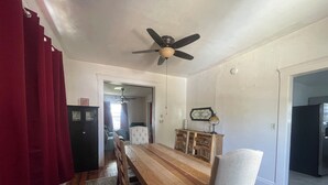 Une salle à manger avec une table en bois, des chaises, un ventilateur de plafond et un tapis.