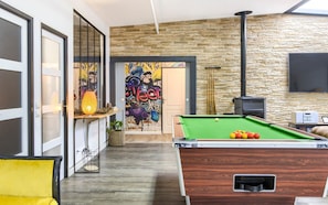 Une pièce moderne équipée d’une table de billard, d’une cheminée et d’un mur décoré de graffitis.
