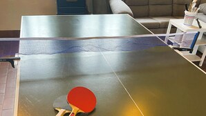 A ping pong table with a net in the center, a red and black paddle, and a blue suitcase in the background. - Beautiful home in Dannemare with WiFi (Dannemare)