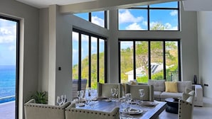 Comedor con una mesa dispuesta para seis personas, ventanas amplias y un ventilador de techo.