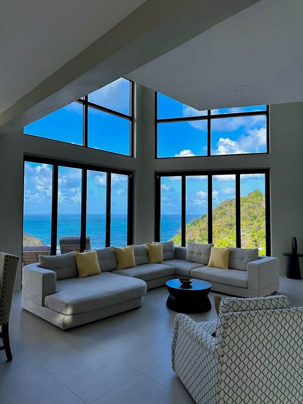 A modern living room with a large sectional sofa, a coffee table, and a patterned armchair.