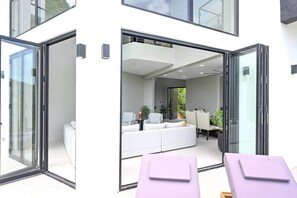 A modern interior with a white sofa, a dining table, and a glass door leading outside.
