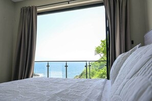 A bedroom with a large window, a bed, and curtains. - Villa Jasiri (Gros Islet)