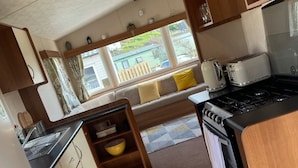 Una cucina compatta per camper con pensili in legno, un fornello e un lavandino.