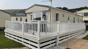 Un'abitazione mobile con una terrazza recintata, un'antenna parabolica e un piccolo portico.