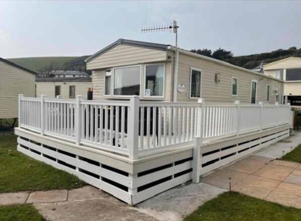 A mobile home with a fenced deck, a satellite dish, and a small porch. - Challaborough bay Caravan, Sleeps 8, pet Friendly (Kingsbridge)