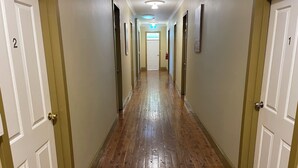 A hotel hallway with wooden floors, white doors numbered 1 and 2, and framed pictures on the walls. - Royal Hotel (Yeoval)
