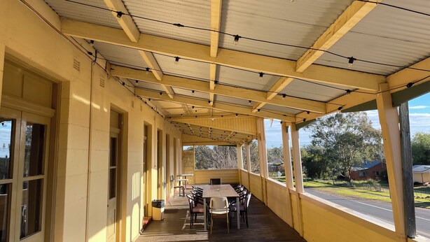 A covered outdoor area with a long table and chairs, large windows, and a view of the surrounding landscape. - Royal Hotel (Yeoval)